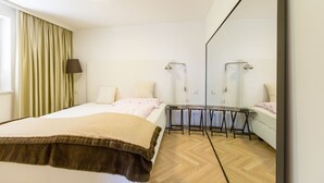 Ein Schlafzimmer mit Bett, Nachttisch, Lampe und einem großen Spiegel.