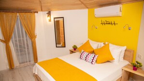 Une chambre à coucher comprenant un lit, une table de chevet, un miroir et un climatiseur fixé au mur.