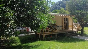 Une petite construction en bois d’un seul étage, dotée d’un porche abrité, entourée d’une végétation luxuriante et bordée d’un chemin de gravier.