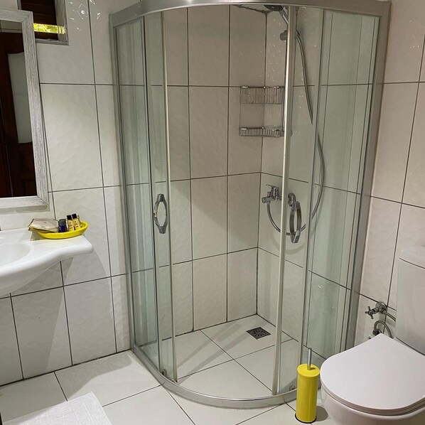 A modern bathroom with a glass-enclosed shower, a white sink, and a toilet.