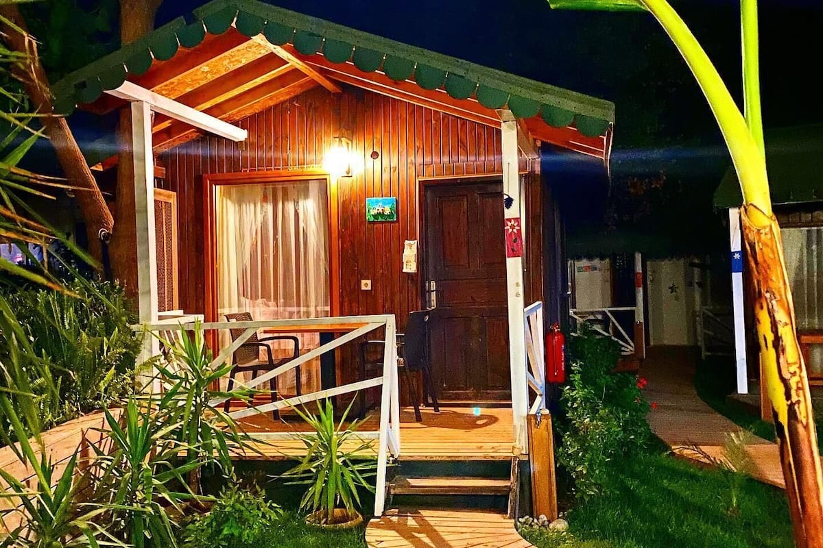 Eine kleine Holzhütte mit einer Veranda, einer Tür, einem Tisch und Stühlen.