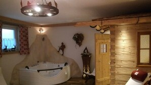 Een wellnessruimte met een groot bubbelbad, houten wanden en een houten deur.