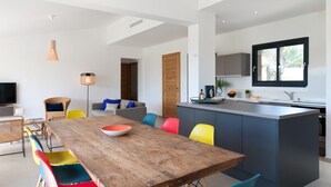 Una cocina moderna con una isla central, un comedor con sillas coloridas y un ventanal que ofrece luz natural.