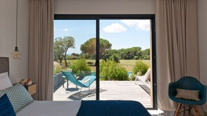 Un dormitorio con una cama grande, vista a una terraza con mobiliario exterior y una puerta corrediza de vidrio que da a un área exterior panorámica.