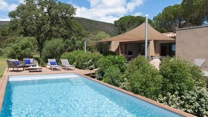 Una piscina con sillas de descanso y un porche cubierto.