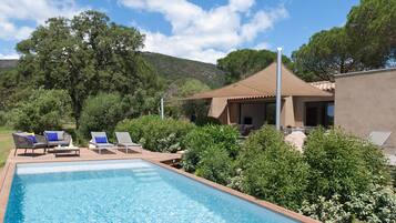 Une piscine avec des chaises longues et un espace patio couvert.