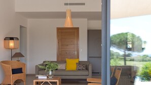 Una sala de estar moderna con un sofá, sillas, una mesa de centro y un ventanal con vistas a un jardín.