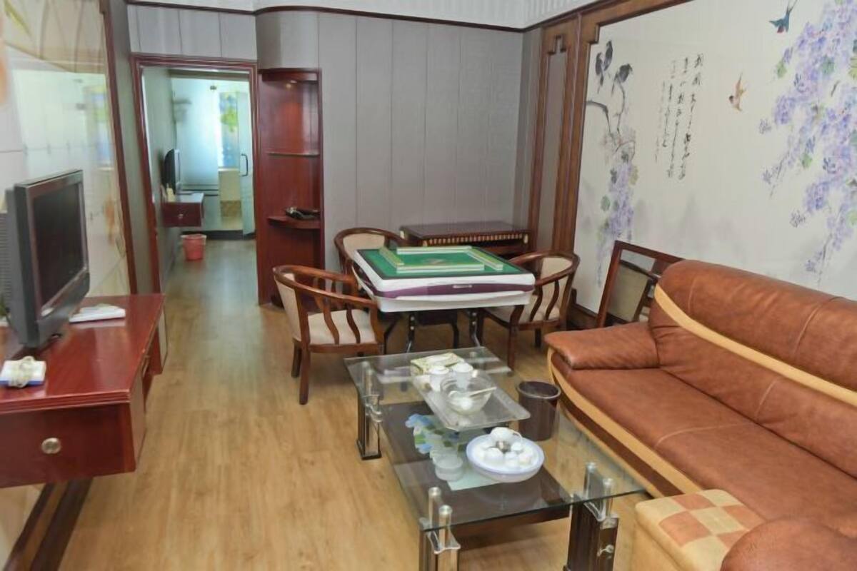 Uma sala de estar com sofá, mesa de centro, televisão e estante de livros.
