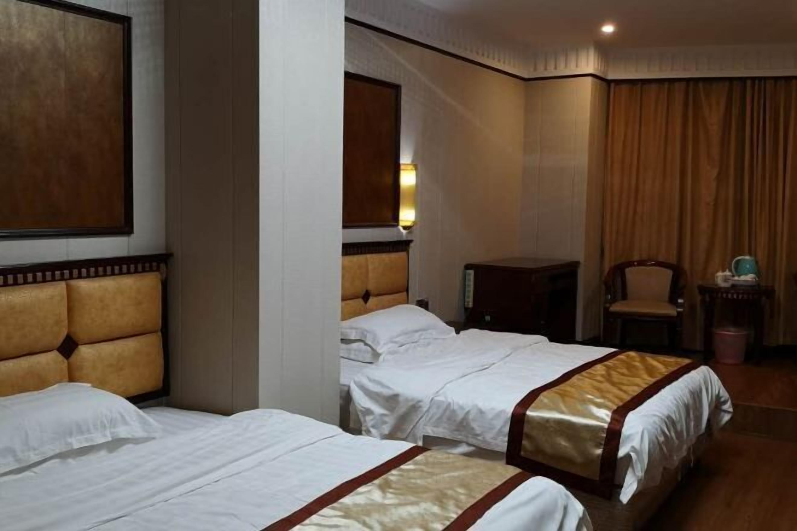 Ein Hotelzimmer mit zwei Betten, einem Holzkopfende, einem Nachttisch, einem Stuhl und einem Vorhang.