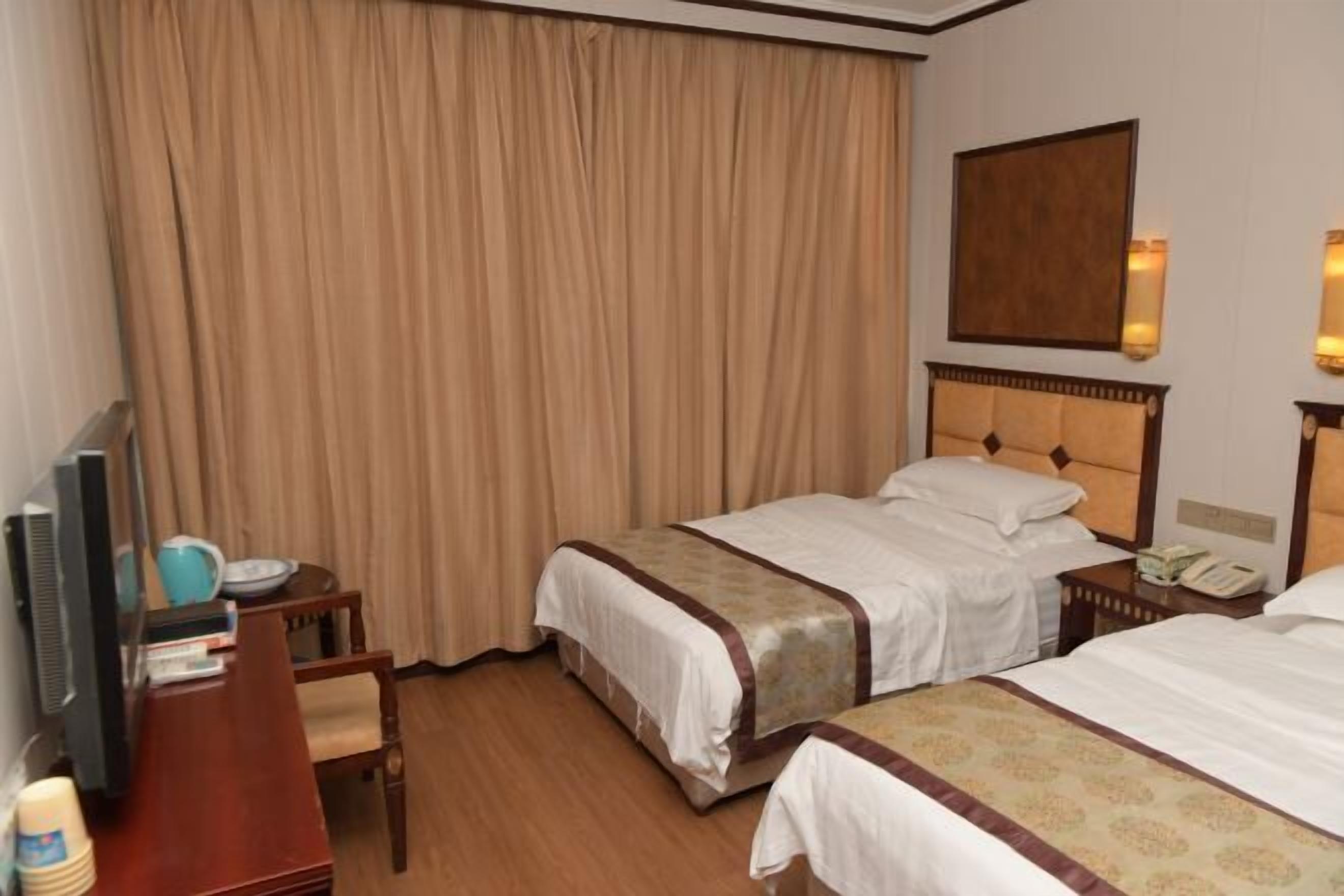 A hotel room with two beds, a desk with a computer, a TV, and a curtain.