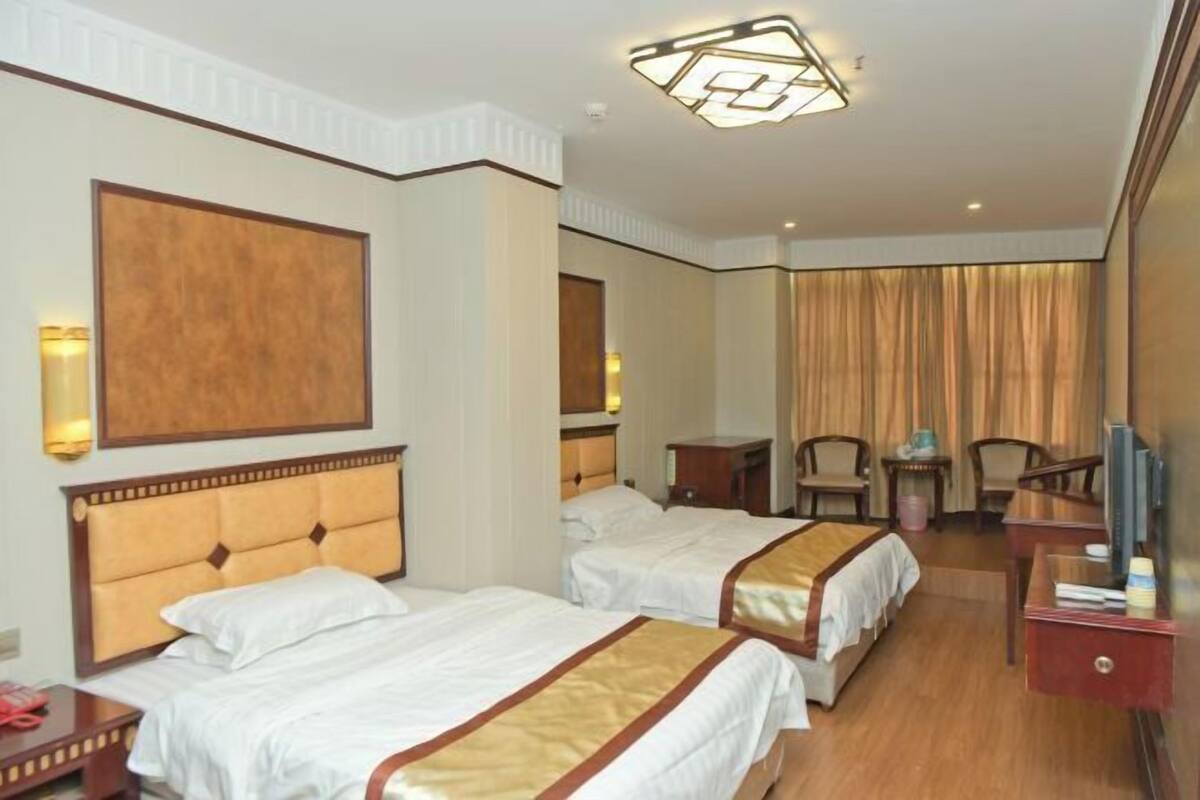 Quarto de hotel com duas camas, televisão, escrivaninha e uma cadeira.