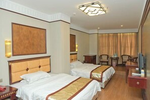 Ein Hotelzimmer mit zwei Betten, einem Fernseher, einem Schreibtisch und einem Sessel.