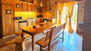 Eine rustikale Küche mit Holzausbau, einer Steinwand und einem großen Holztisch.