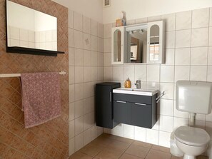 Ein Badezimmer mit Toilette, Waschbecken mit Spiegel darüber und einem Handtuch an einem Halter.