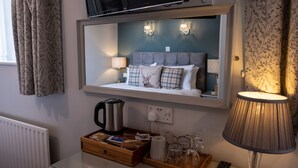 A hotel room with a bed, a bedside table with a lamp, a coffee maker, and a tray with toiletries. - Sunnyside B and B (Keswick)