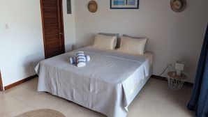 A neatly made bed with a striped blanket and pillows, a small bedside table with a lamp, and a framed picture on the wall.