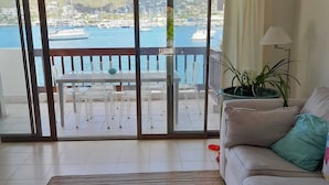 A living room with a view of a marina, a sofa, a coffee table, and a potted plant.