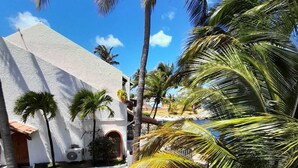 A white building with a red roof, surrounded by palm trees and a well-maintained lawn.