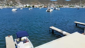 A marina with boats docked, a pier, and a mountainous backdrop.