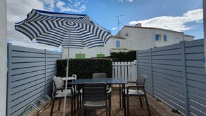 A patio area with a table and chairs, a striped umbrella, and a white fence. - Sunny cottage near the beach for 4 pers. in La Faute-sur-Mer (La Faute-sur-Mer)