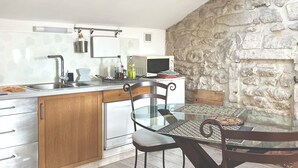 Cozinha moderna com ilha central, eletrodomésticos de aço inoxidável e parede de pedra.