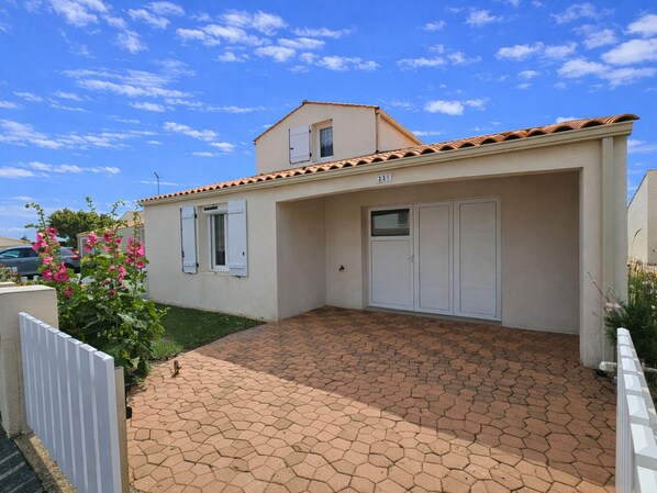 A two-story house with a tiled roof, a garage, and a paved driveway.