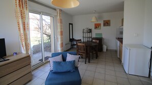 Ett kompakt bostadsutrymme med en soffa, ett matbord och ett litet kök.