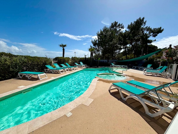 A swimming pool with multiple lounge chairs and a palm tree.