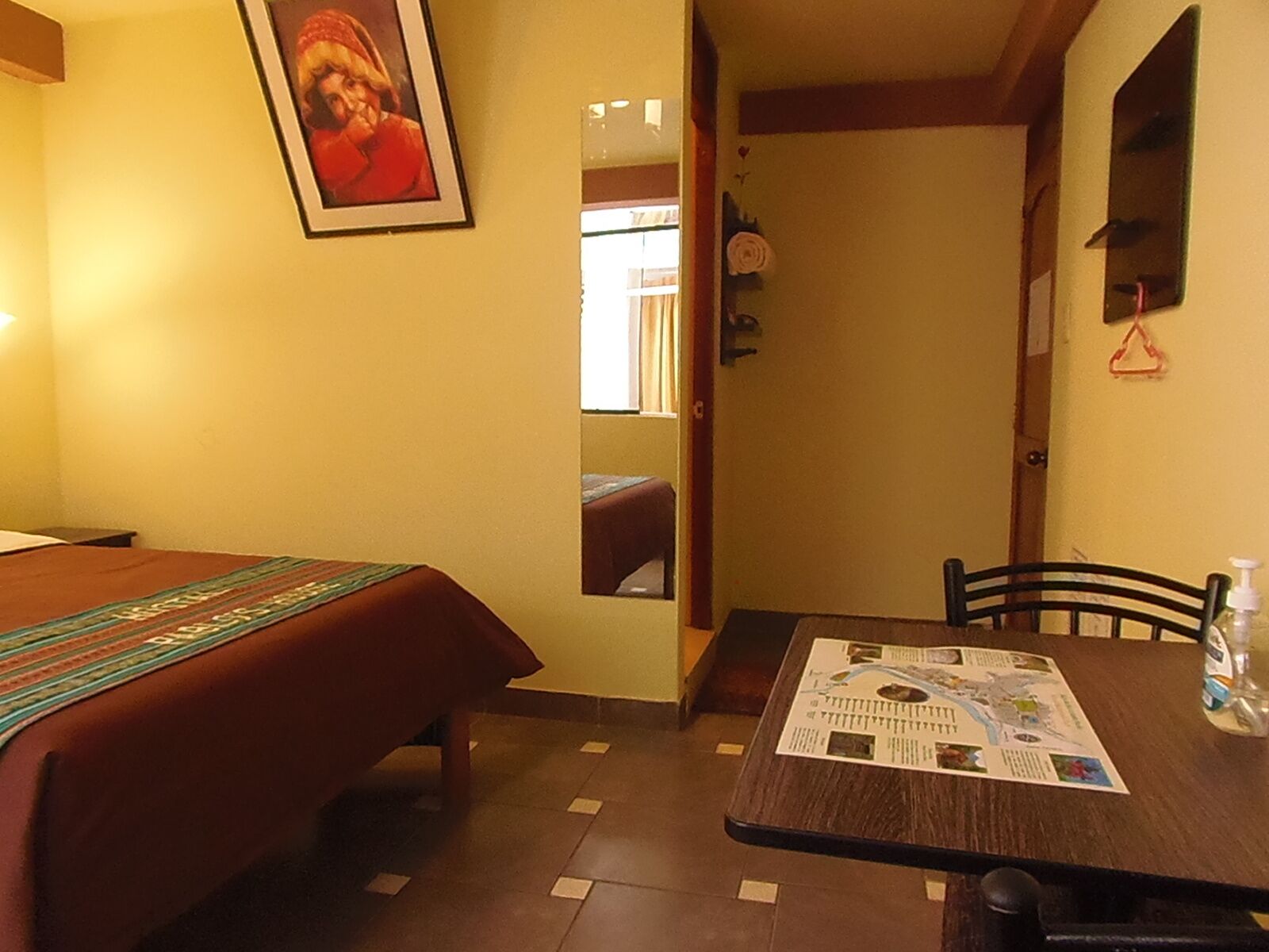 A hotel room with a bed, a dining table with a menu, and a mirror on the wall.