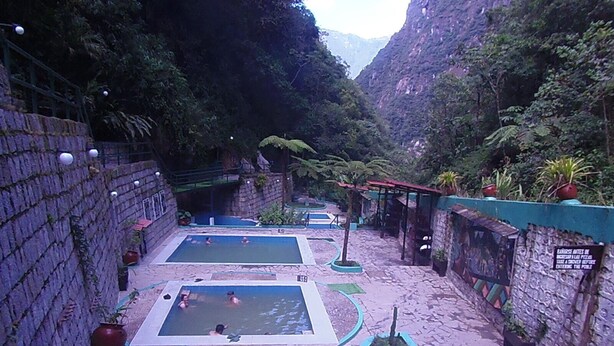 A pool area with multiple pools, stone walls, and potted plants. - Hostal Pablos House (Machu Picchu)