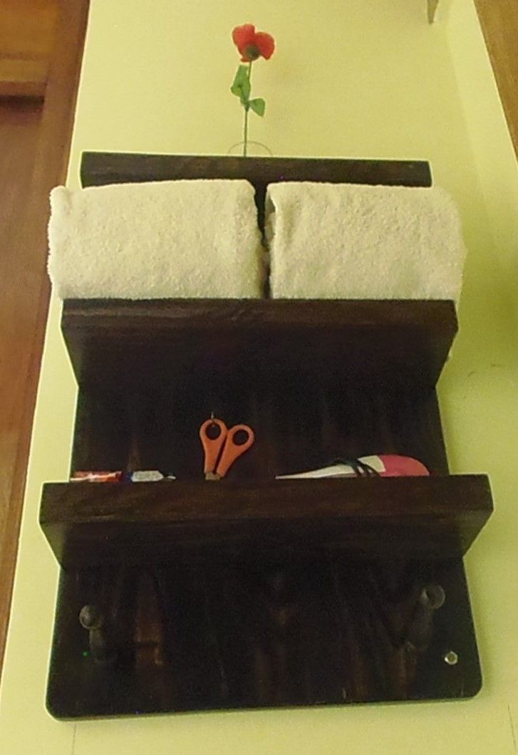 Een donker houten plank met twee witte handdoeken en een schaar.