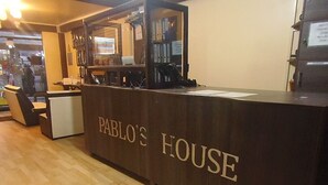 A reception desk labeled "Pablo's House" with a computer monitor, papers, and a telephone. - Hostal Pablos House (Machu Picchu)