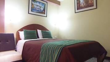 Una camera d'albergo con un letto, una sedia e due quadri appesi al muro.