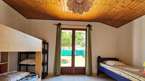 A dormitory room with bunk beds, a tiled floor, a wooden ceiling, and a window with curtains. - Quiet house near beach, pets allowed (La Faute-sur-Mer)