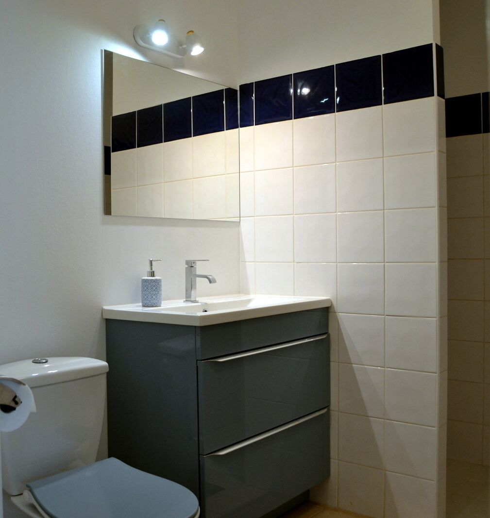 Ein Badezimmer mit Toilette, Waschbecken und einem Spiegel darüber sowie einem Unterschrank.