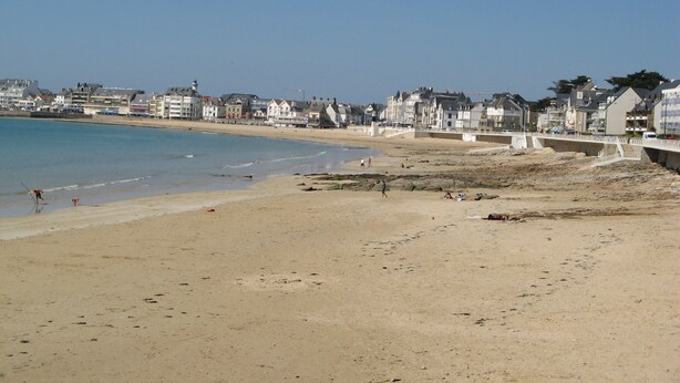 A beach with a sandy shore, a pier, and buildings in the background. - Apartment with garden in quiet residence near beaches wi fi parking (Quiberon)