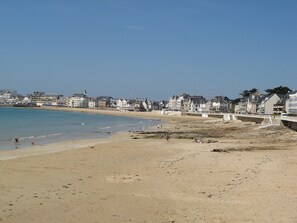 A beach with a sandy shore, a pier, and buildings in the background. - Apartment with garden in quiet residence near beaches wi fi parking (Quiberon)