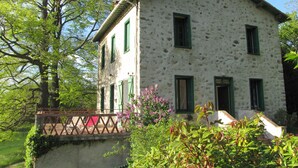 A two-story stone building with green shutters, a balcony, and a garden with flowering plants. - Mas Soubiranne on the heights of Céret (Céret)