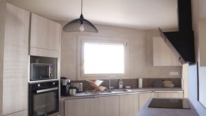 Een moderne keuken met houten kastjes, een ingebouwde magnetron, een oven, een koffiezetapparaat en een waterkoker.