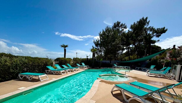A swimming pool with multiple lounge chairs and a palm tree. - Luxury apartment for 4, beachfront, balcony, pool, pets allowed, parking, WiFi (La Tranche-sur-Mer)