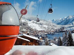A ski lift chair, a sign with 'Chalet 8' and 'Clafoutis,' and a snowy mountain town.