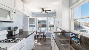 Une cuisine moderne avec des meubles blancs, une cuisinière à gaz, un évier et un coin repas comprenant une table et des chaises.