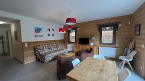 A wooden cabin interior with a sofa, a table, a TV, and a window. - Spacious 3* Apartment - 6 ppl with balcony in Châtel (Châtel)
