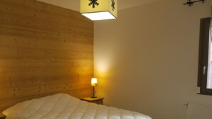 A bedroom with a wooden headboard, a bedside lamp, a window, and a radiator. - Spacious 3* Apartment - 6 ppl with balcony in Châtel (Châtel)