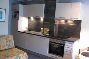 A compact kitchen with white cabinets, a microwave, an oven, and a coffee maker. - Apartment with terrace Ideally Located In Quiet Residence wi-fi near beach (Quiberon)