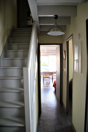 A staircase leading to a second floor, a hallway with a ceiling light, and a view into a dining area with a table and chairs. - Apartment with terrace Ideally Located In Quiet Residence wi-fi near beach (Quiberon)