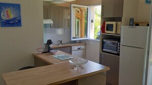 Cocina compacta con ventana, microondas y un lavamanos pequeño.