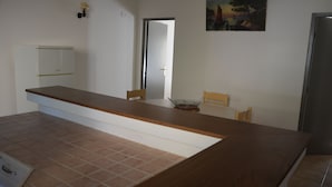 Une pièce avec un comptoir en bois, une armoire blanche, une porte et un tableau accroché au mur.