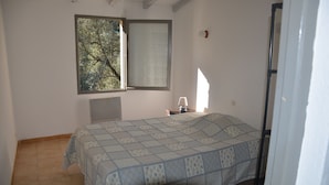 Une chambre à coucher avec un lit, une fenêtre, une table de chevet et une lampe.