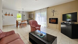 Una sala de estar moderna con una mesa de centro de vidrio, un sofá de cuero, un televisor en un mueble bajo y un comedor con una mesa y sillas.